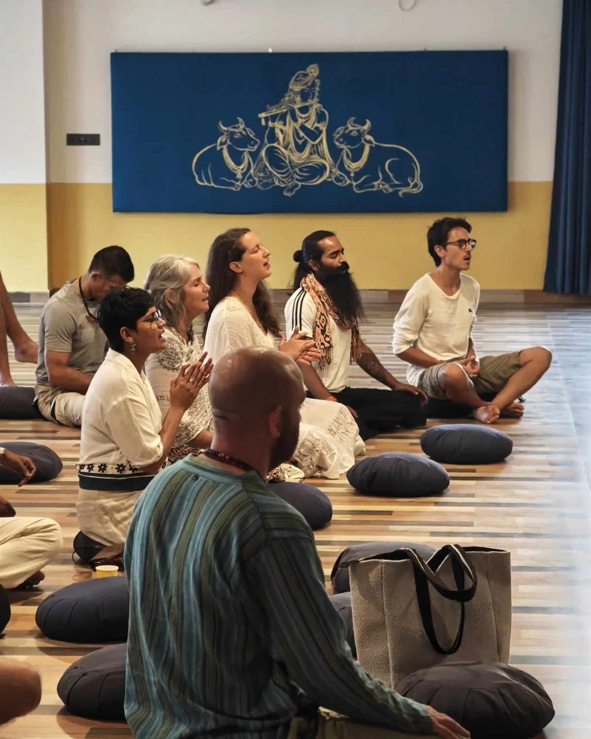 The community chanting together beneath the Krishna banner in the ashram hall