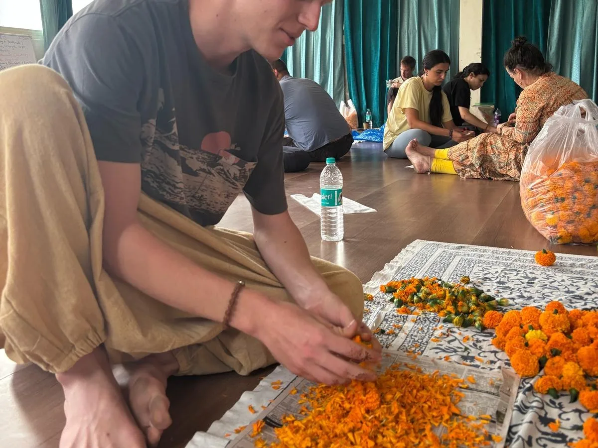 Preparing marigold garlands together during a workshop in the hall