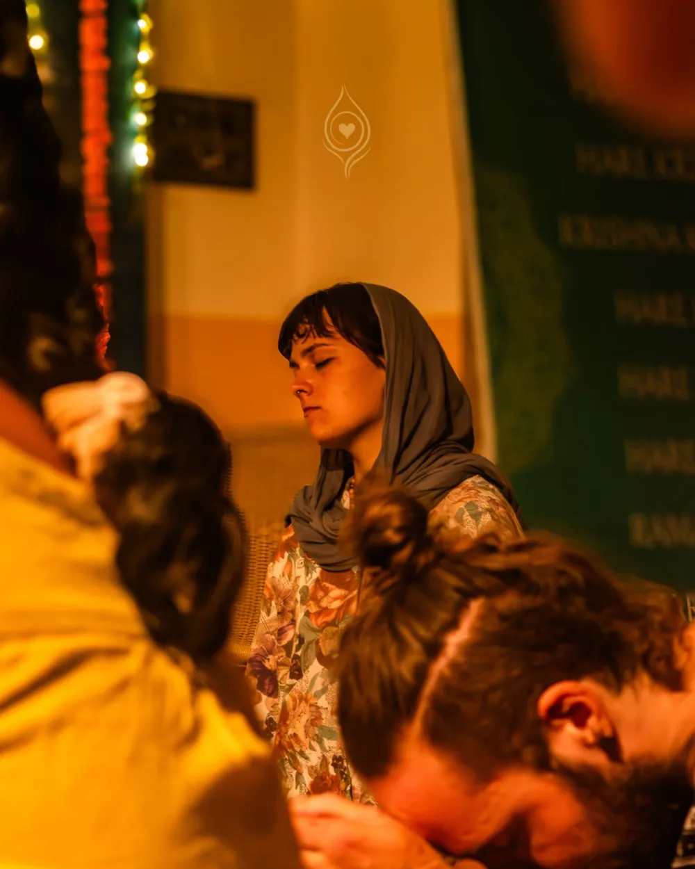 A visitor sits in quiet devotion during an evening gathering at the kirtan hall