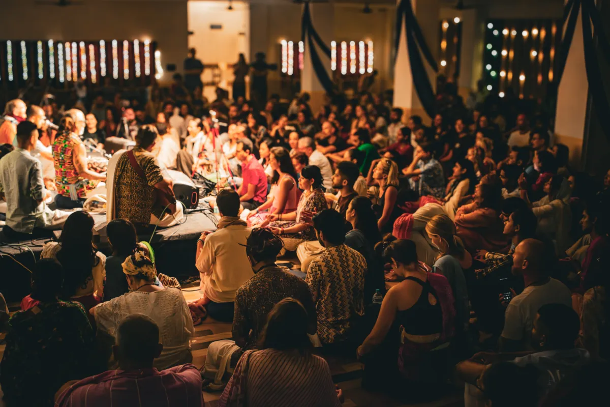 The crowd singing together under fairy lights at a Kirtan Mela evening